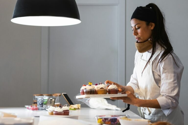 Female cook with cupcakes in kitchen